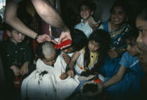 Hindu family participating in head shaving of young son.
