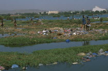 View over the city across a rubbish tip and River Niger with people scavenging  amongst the waste.