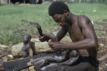 Makonde man carving traditional wooden sculpture.
