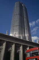 Tower 42Previously known as the Nat West Tower  skyscraper towers over neoclassical building in foregroundred London bus in right hand corner of image