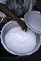Hand stirring yogurt being mage in aluminium bowl.