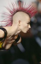 Woman with Pink spiked hair running in narrow strip down her head and a ring through her bottom lip at Alternative Fashion Show.