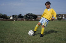 Young boy kicking football.