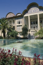 Ghajar Palace Kakh -E -Eram Garden of Paradise. Palace exterior seen from across a pool with flowers in the foreground