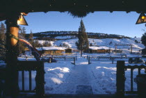 View of Guest cabins at the Triangle C Dude Ranch in the snow from building framed with Christmas lights