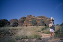 Purnululu or Bungle Bungle. Woman wearing straw hat taking picture of striped rock towers