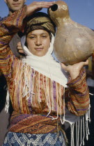 Young woman carrying calabash gourd for water.