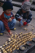 Children lighting oil wick candles at Kumbeshwar Mahadev TempleHindu