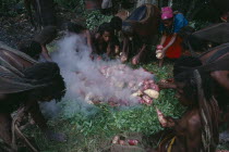 Dani tribeswomen steaming sweet potatoes in traditional oven made from grass and hot stones.