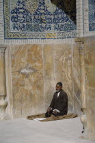 Man with prayer beads praying beside wall of mosque. Isfahan