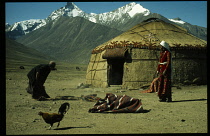Kirghiz nomads shaking out rugs beside yurt.Paleo-Siberian women ger yurt