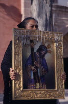 Mourner carrying portrait of Christ at Good Friday procession