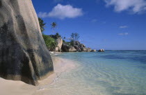 Anse Source D Argent. View from behind large rock boulders on golden sandy beach looking along coastline
