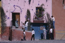 People decorating exterior of house with palm fronds and streamers for Palm Sunday celebrations. Easter
