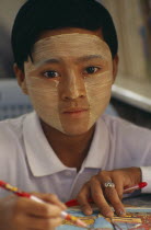 Young girl wearing thanaka paste on her face in traditional Burmese style.