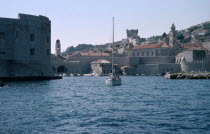 The Old City harbour with stone fort and a yacht sailing on the water