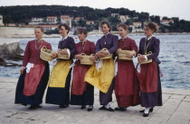 Girls in traditional clothing holding baskets greeting arriving visitors