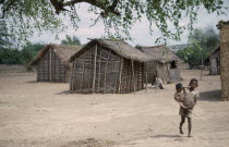 Village homes with a young girl carrying a younger child in the foreground