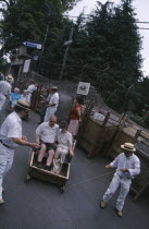 Tourists starting their Toboggan ride down to Funchal guided by two drivers