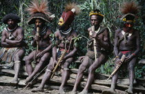Southern Highlands. Huli tribe men sat together playing wood instruments at Bachelor Boys centre