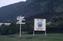 Sign with Welcome to the Loneliest Island written on it next to a direction sign postTristan da Cunha is a group of remote islands in the south Atlantic Ocean. It is a dependency of the British overs...