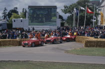 Festival of Speed. Three red Ferraris 2 litre built in 1950 4.1 litre 1953 and 4.1litre 1957. Crowds of spectators gathered around circuit