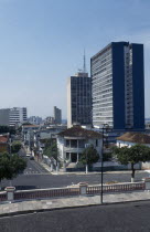 Downtown area. View across a road towards a street of houses with high rise buildings behind Brasil