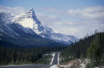 Trans-Canada highway through mountain landscape with pine forests and melting snow.