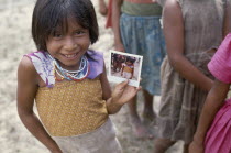 Macuna Indian girl holding a polaroid photograph of herself.