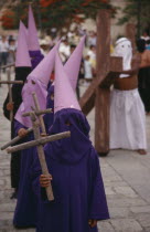 Young  masked penitents carrying wooden crosses during Easter parade.