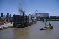 Tugboat and container ship in dock.
