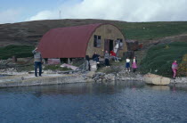 View across water towards loading jetty with a family near building