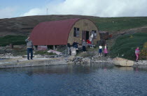 View across water towards loading jetty with a family near building