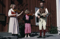 Folk musicians with woman and girl playing violins and man playing Nyckelharpa