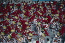 Carnival procession of dancers wearing red feathered head dressesBrasil