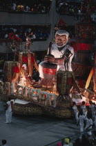 Carnival float with large model of a man surrounded by dancersBrasil