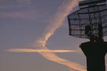 Radar scanner in the foreground  at London Heathrow with vapour trails in the sky in the shape of an aeroplane