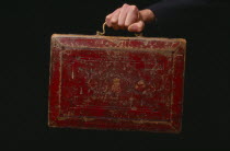 Hand holding the old red leather Budget briefcaseEngland England