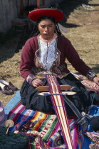 Kneeling woman in traditional costume hand weaving decorative textile.