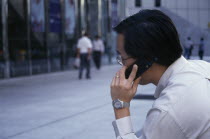 Profile of city worker on mobile phone in the street in the financial centre of OUB Plaza