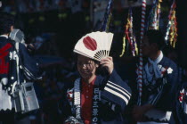 Woman at the autumn Sake Festival holding a fan with the design of the Japanese flag on it