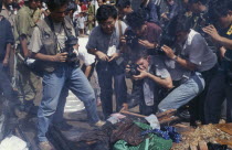 Press photographers taking close up photographs of a bonfire of the looted contents of the Khmer Rouge offices during an anti Khmer Rouge demonstration