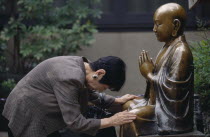 Woman praying before a seated Buddha