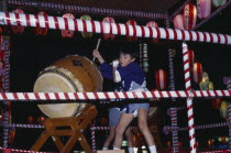 Young boy in costume beating a large drum at the O-Bon festival