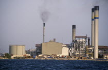 Seawater desalination plant exterior with narrow chimney emitting black smoke.Netherlands AntillesDutch  air pollution