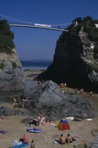 Partial view of town beach  children play at the foot of two large rocks that a bridge spans