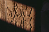 Relief carving of three figures and hieroglyphics In shadow