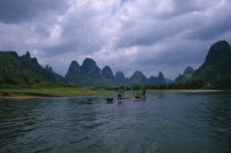 Cormorant fishermen on rafts on the River Li with limestone karst mountains in the distance