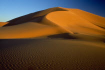 Orange desert sand dunes against a clear blue sky