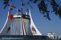 Falcon Fountain with flags flying on the top framed by  tree branches. Part of the Hotel Intercontinental.United Arab Emirates